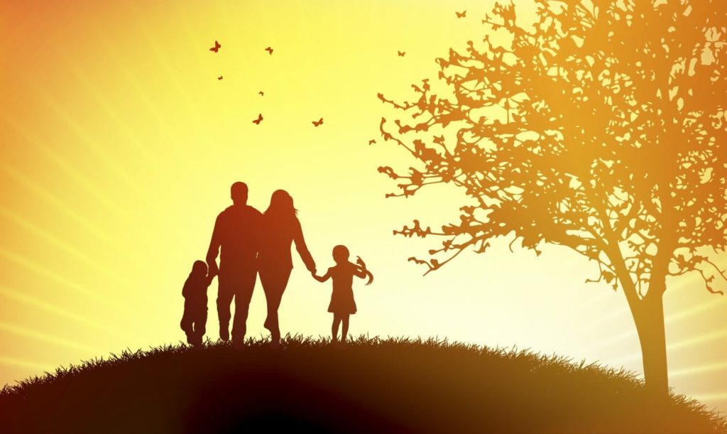 A family stands on a grassy hill, walks into the sunset holding hands. A tree and some flying butterflies complete the scene.
