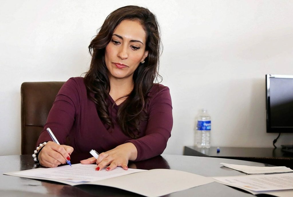 A woman credit union member signs paperwork in an office setting.
