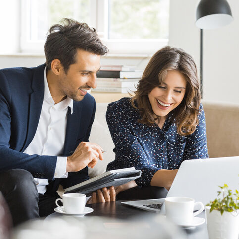 Two colleagues working at laptop smiling.