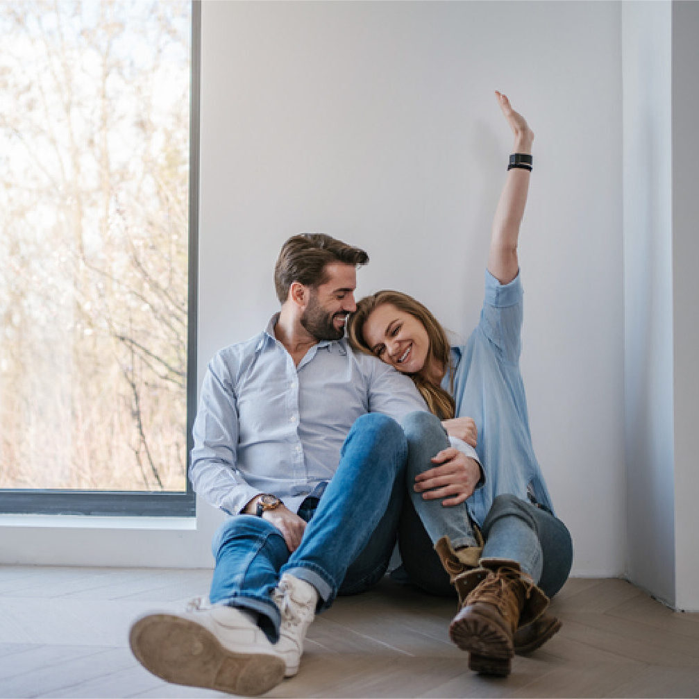 Couple excited to be sitting on the floor of their new apartment.