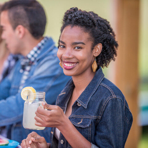 Woman smiling holding a glass of cold lemonade.
