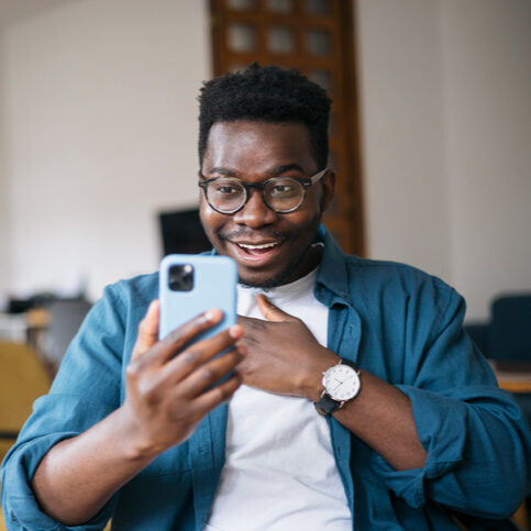 Man looking at phone while smiling with relief.