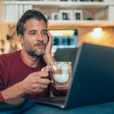 Photo of a man intently watching the QCash demo on a laptop with a mug of coffee in his hand.