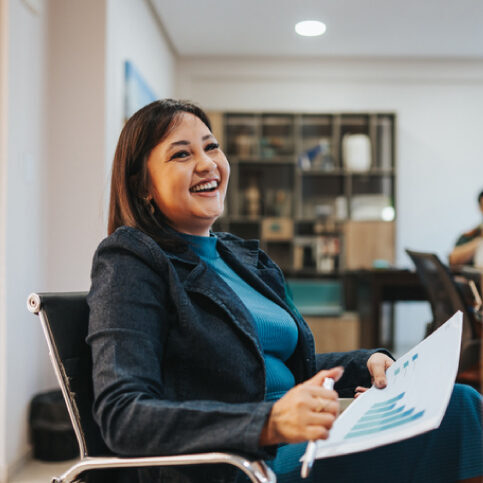 Woman in office holding a report and smiling.