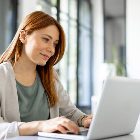 Photo of a woman smiling while on a laptop.